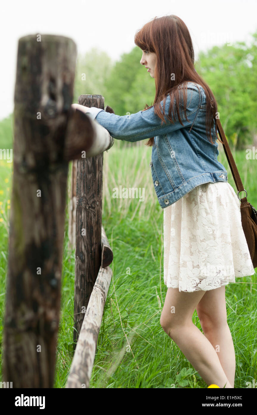 Young woman leaning on wooden fence Stock Photo