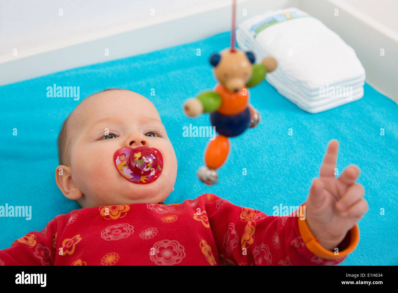Contented 7 month old baby girl playing with dangling teddybear Stock Photo