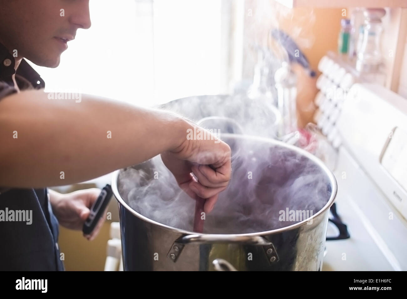 Mid adult man stirring home brew beer in pan Stock Photo