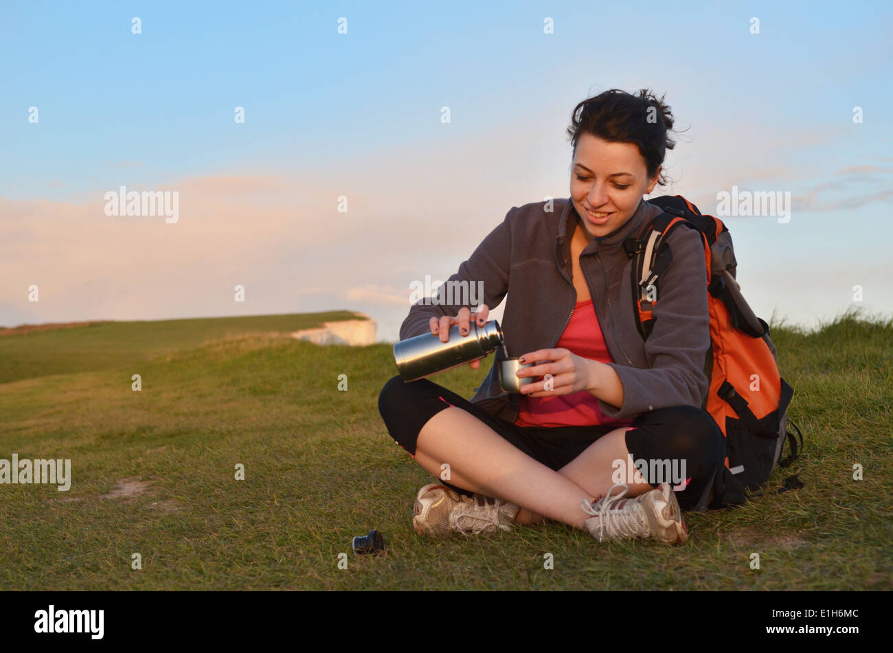 Young female hiker pouring coffee flask on cliff top Stock Photo