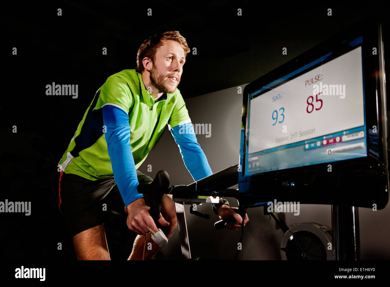 Young man on gym exercise cycle in altitude centre Stock Photo