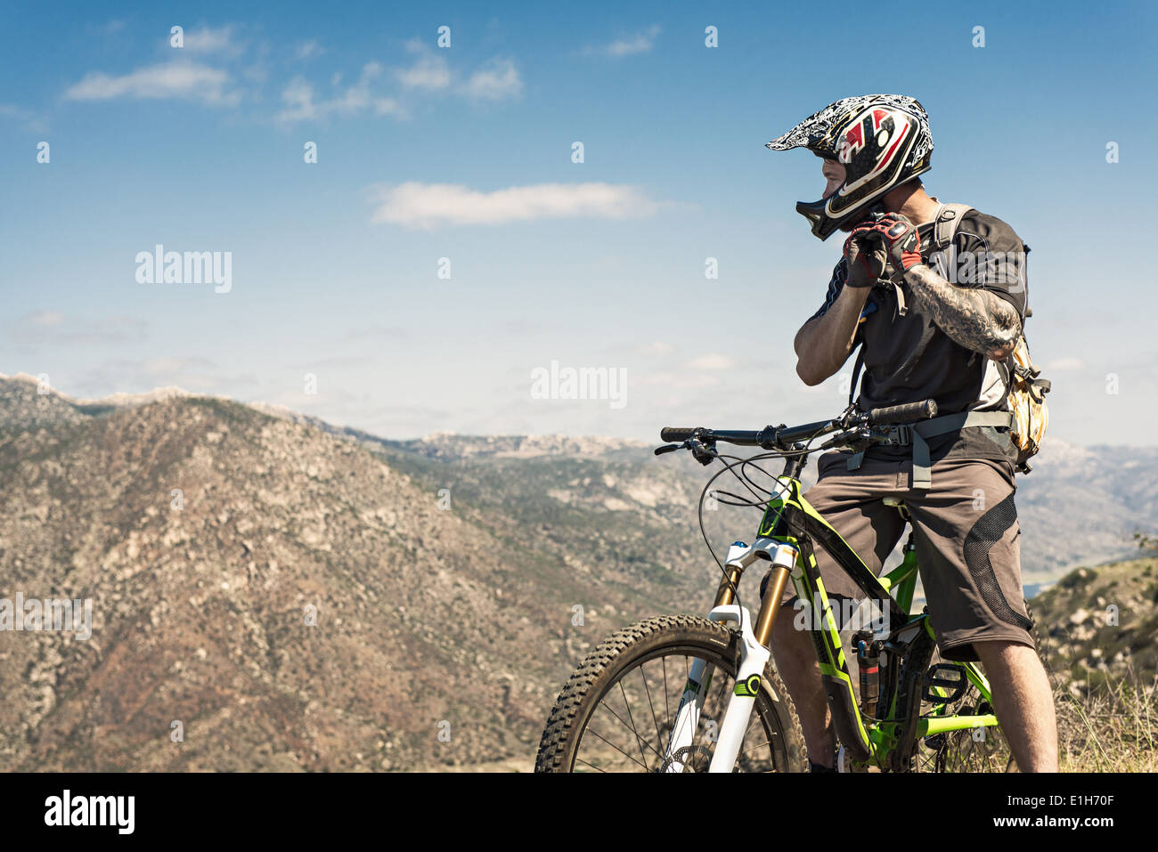 Downhill mountain biker putting on helmet Stock Photo