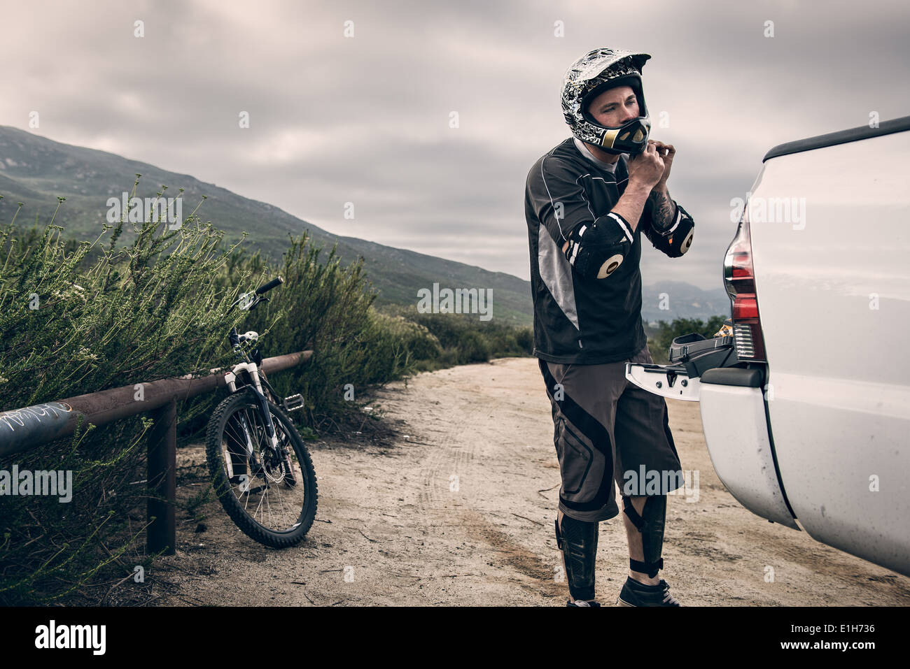 Downhill mountain biker putting on helmet Stock Photo