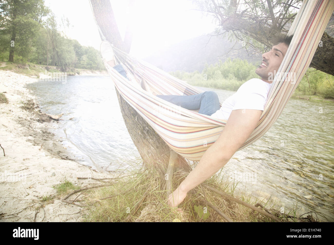 Young man lounging in hammock on Toce riverbank, Piemonte, Italy Stock Photo