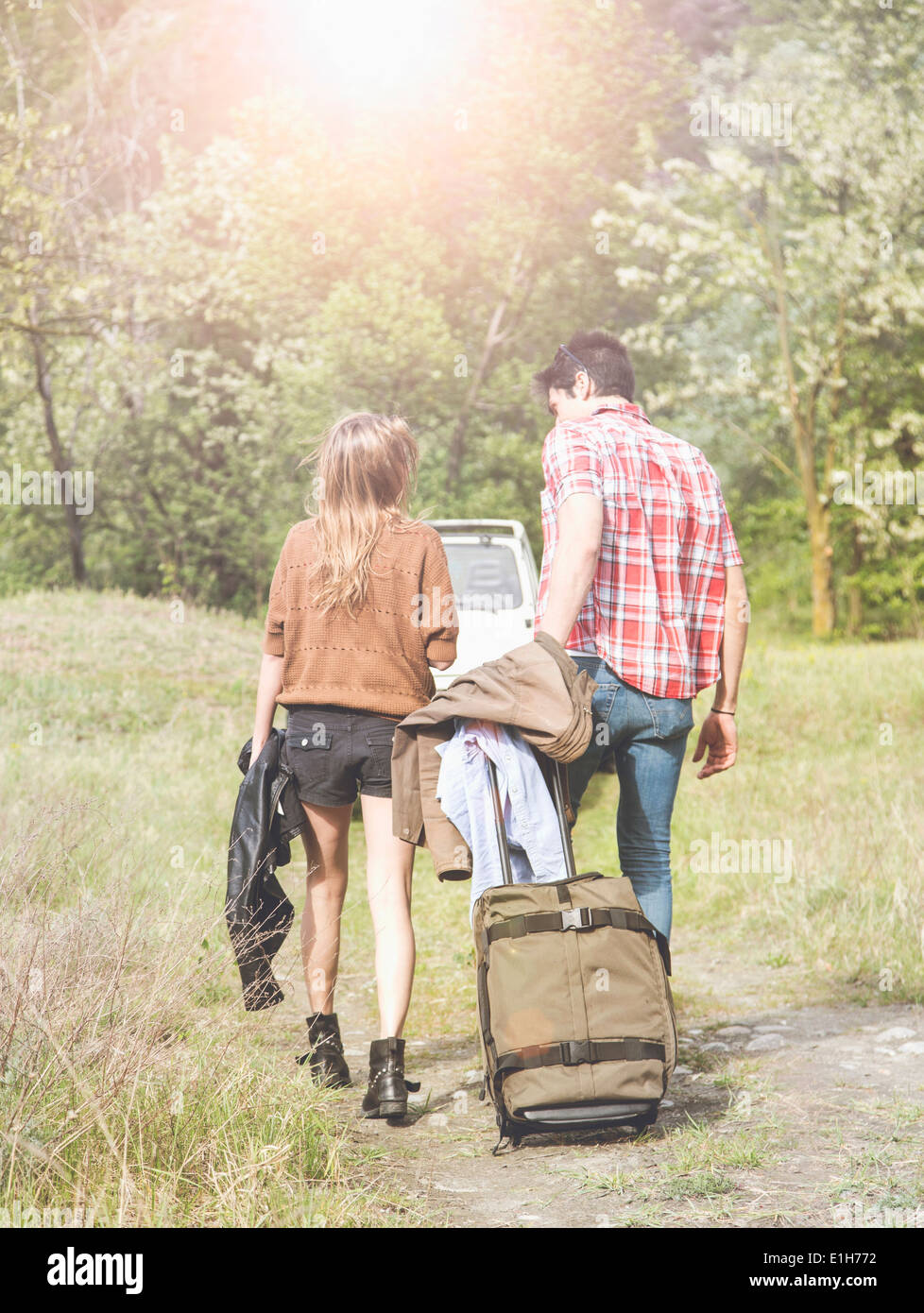 Young couple with wheeled suitcase heading for pick-up truck, Piemonte, Italy Stock Photo