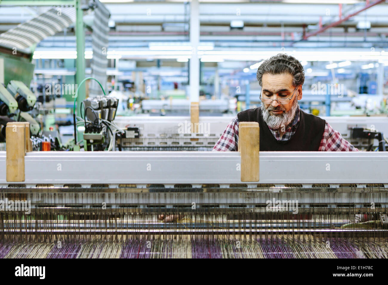 Male factory worker on weaving machine in woollen mill Stock Photo
