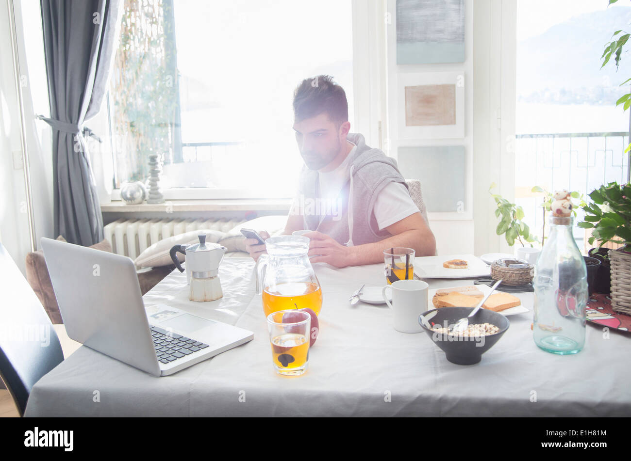 Young man having breakfast and using laptop Stock Photo