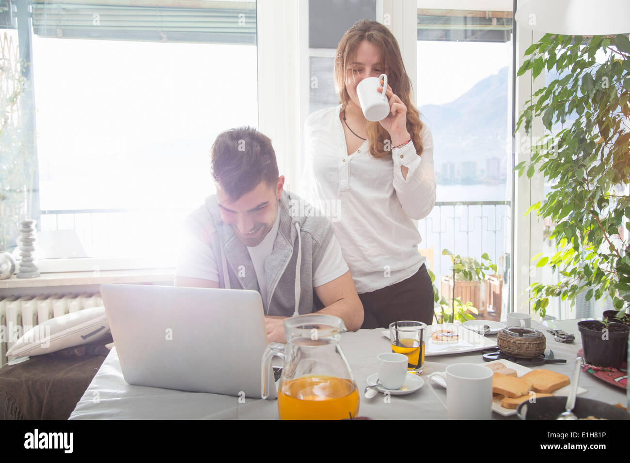 Young man having breakfast and using laptop Stock Photo