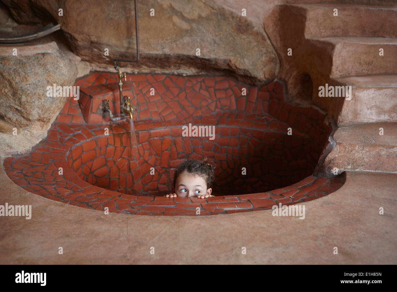 Girl peeking over rustic bath in floor Stock Photo