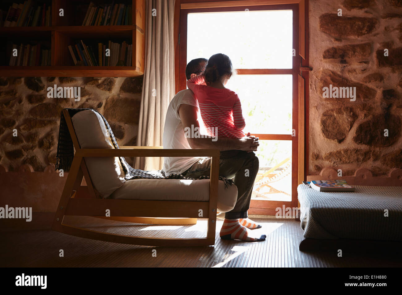 Mid adult man and daughter looking out of window Stock Photo