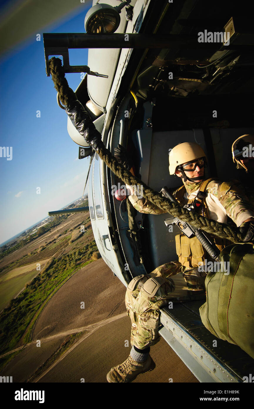 A U.S. Sailor rides in an MH-60 Seahawk from Helicopter Sea Combat Squadron (HSC) 28 during rope suspension training with Sailo Stock Photo