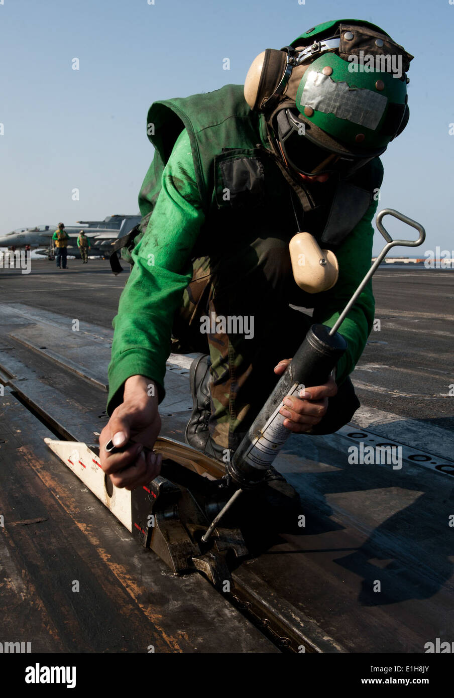 U.S. Navy Aviation Boatswain's Mate Airman Krzysztof Urbanik greases the catapult shuttle on the