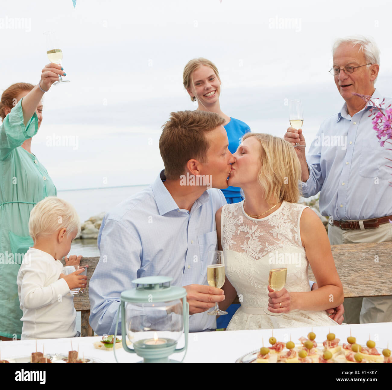 Mid adult couple kissing and making a toast with group of friends Stock Photo