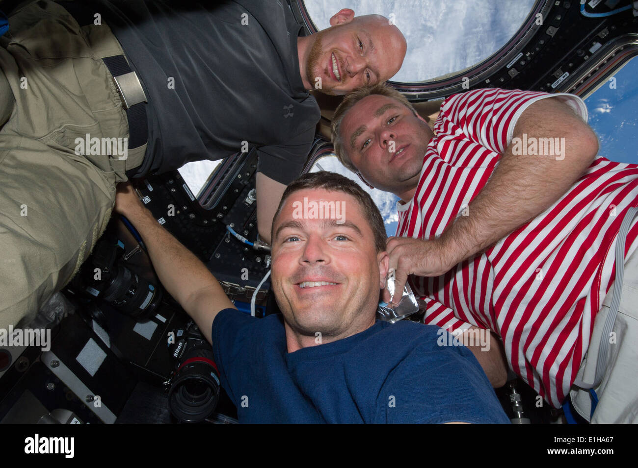 Newly arrived Expedition 40 crew members European Space Agency astronaut Alexander Gerst, left, NASA astronaut Reid Wiseman, center, and Russian cosmonaut Maxim Suraev pose for a photo in the Cupola of the International Space Station June 2, 2014 in Earth Orbit. Stock Photo