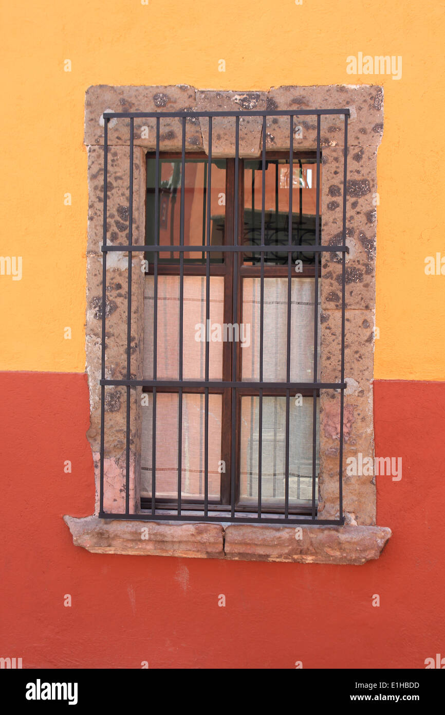 Colonial-style window with wrought-iron railings in red and yellow wall, San Miguel de Allende, Guanajuato, Mexico Stock Photo