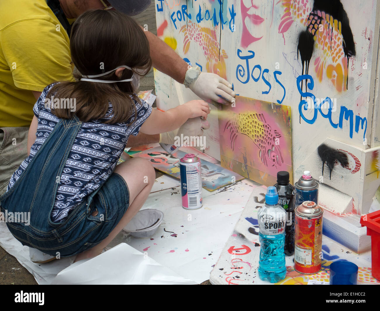 A young girl learns how to stencil using spray paint to make graffiti street art during the Portsmouth street games 2014 Stock Photo