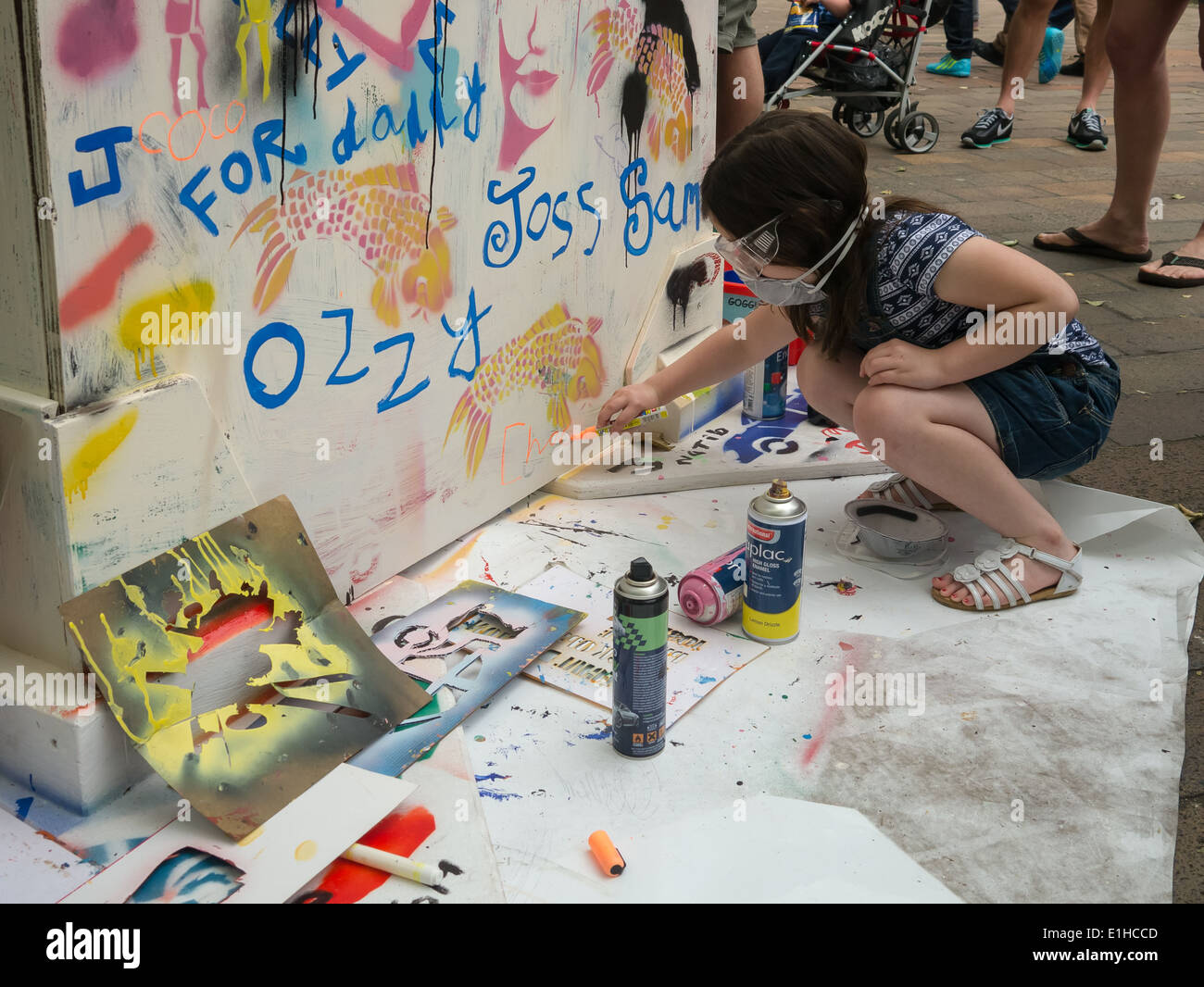 A young girl learns how to stencil using spray paint to make graffiti street art during the Portsmouth street games 2014 Stock Photo