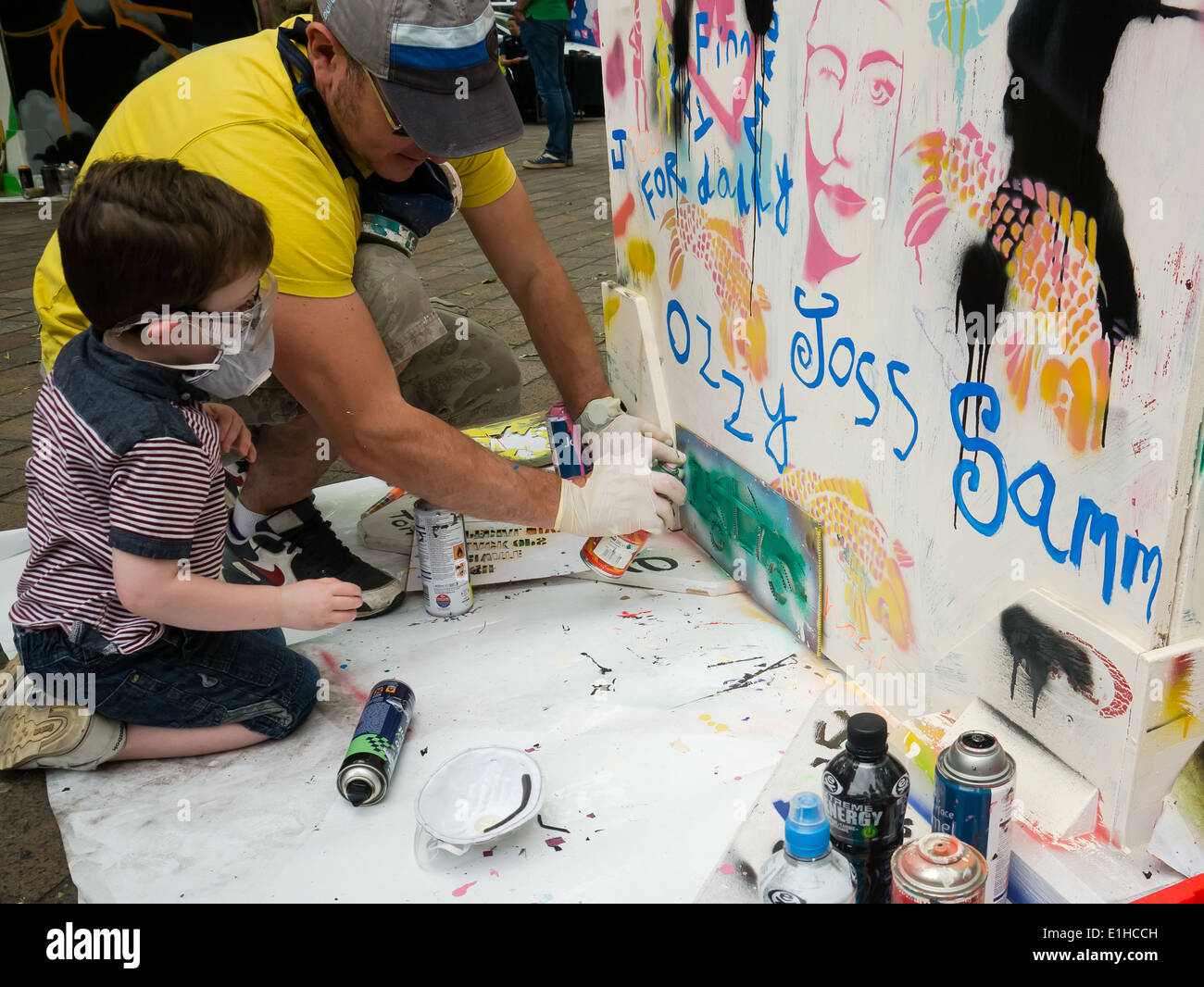 A young boy learns how to stencil using spray paint to make graffiti street art during the Portsmouth street games 2014 Stock Photo