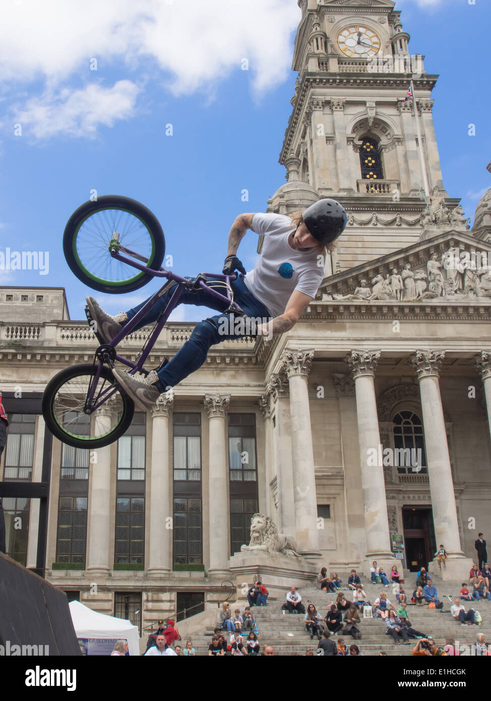 A BMX rider performs an aerial stunt in front of crowds gathered on the Portsmouth Guildhall steps, during the Portsmouth street Stock Photo