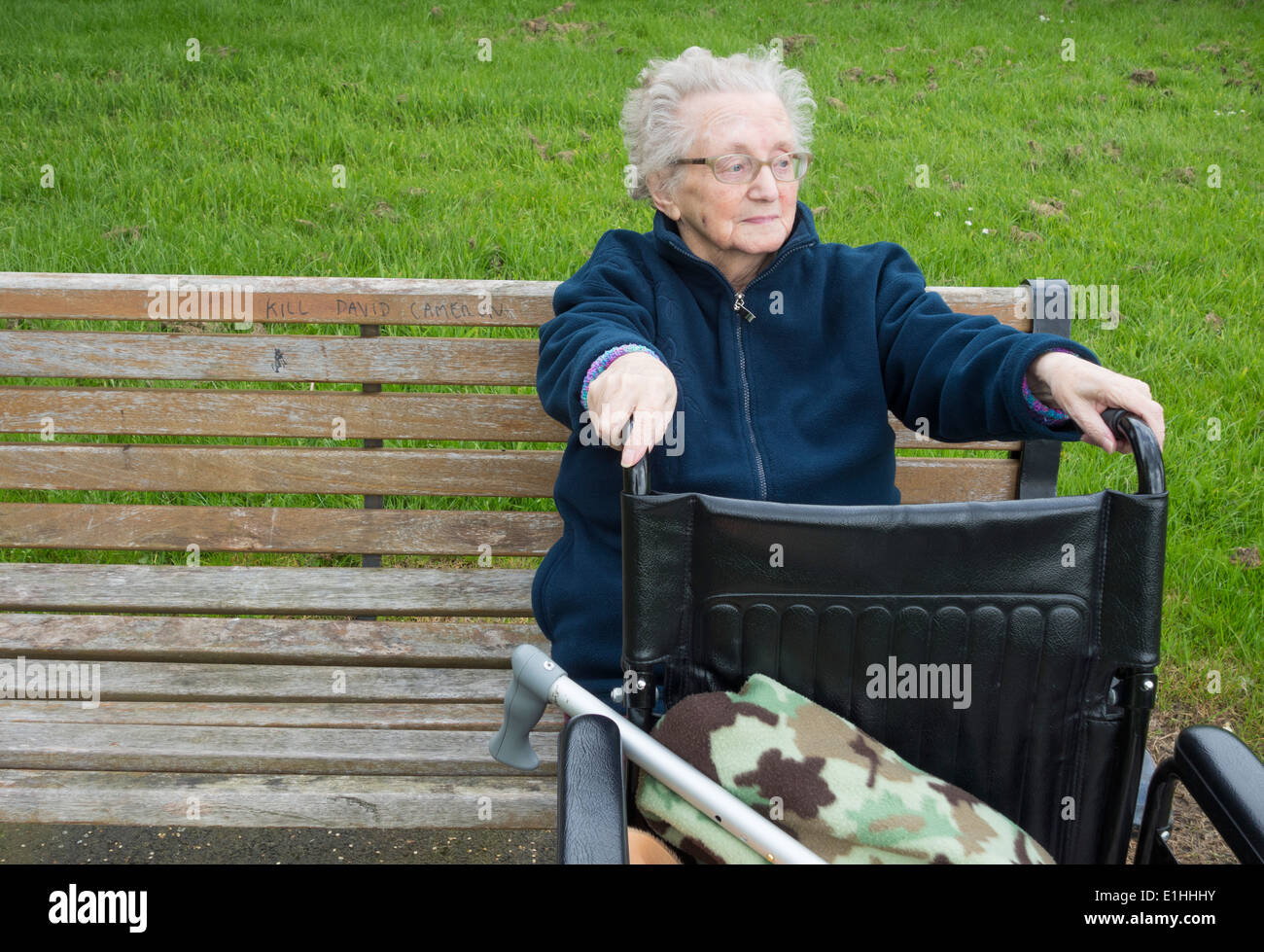 Ninety year old lady sitting on park bench in Autumn in England. UK Stock Photo