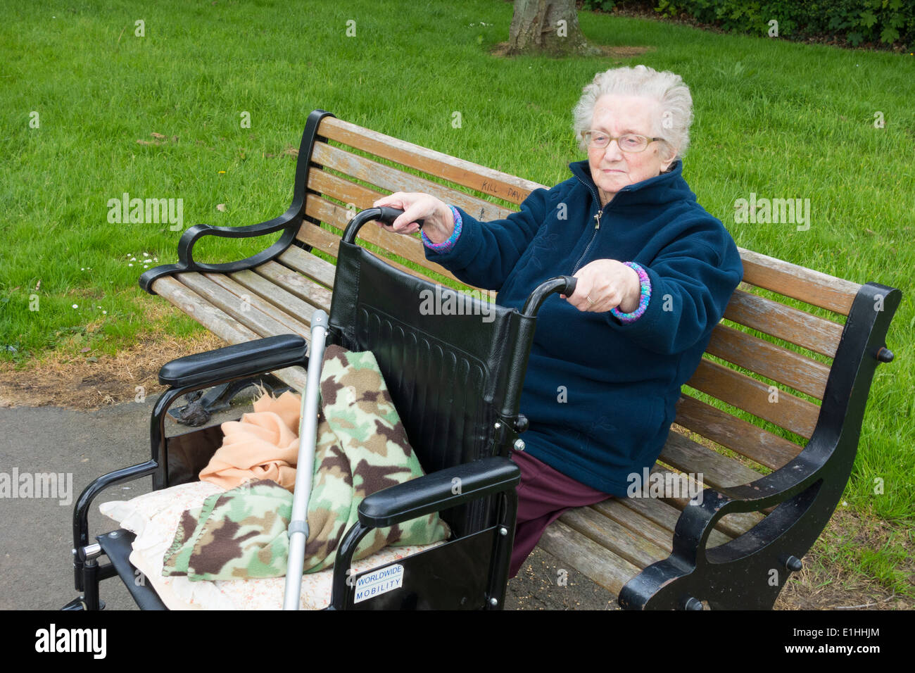Ninety year old lady sitting on park bench in Autumn in England. UK Stock Photo