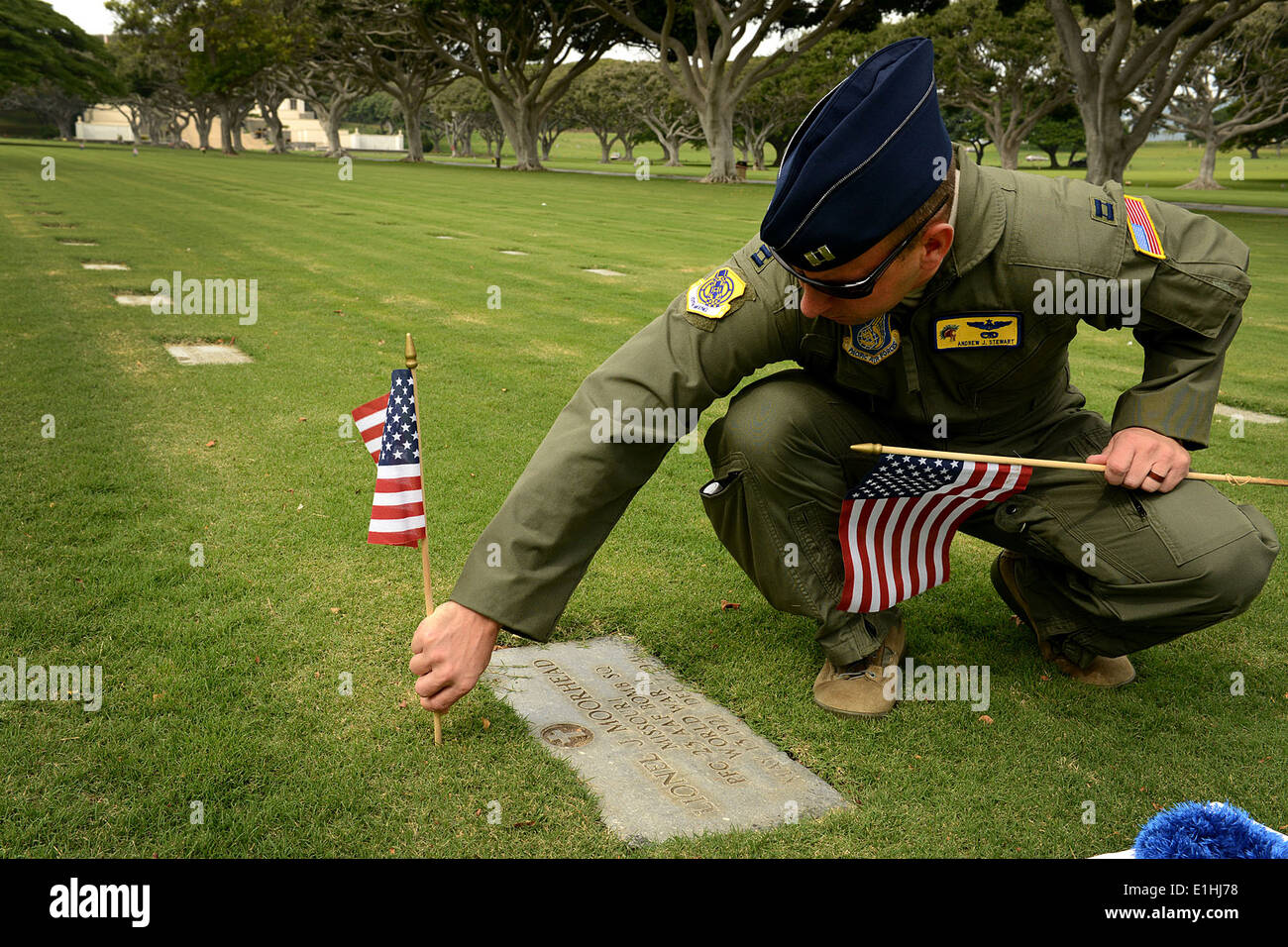Capt. Andy Stewart, 15th Wing commander’s Action Group, places an American flag and handmade lei at the top of a gravesite, D Stock Photo
