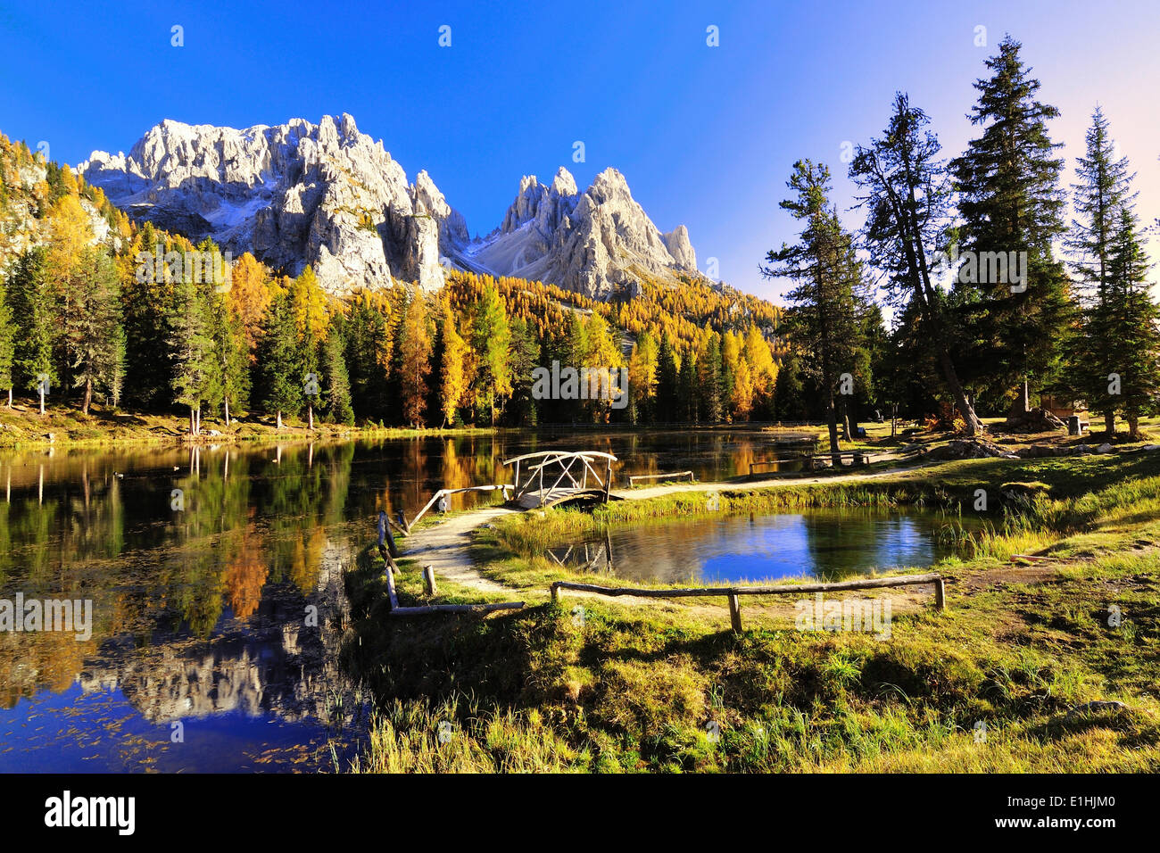 Autumn at Lake d'Antorno with a wooden bridge and the reflection of the Cadini Misurina Mountains, Dolomites, Belluno province Stock Photo