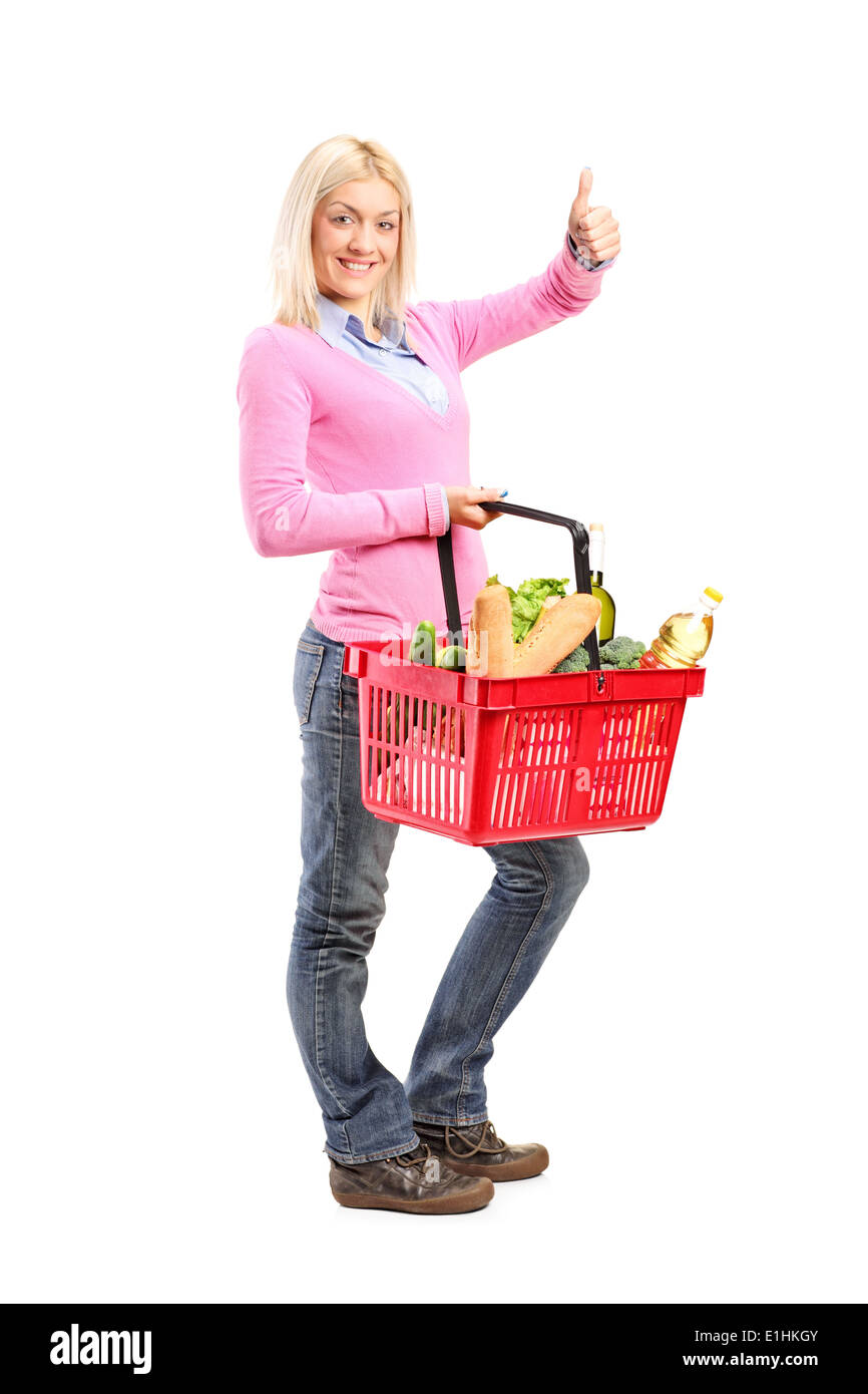 Young girl holding a shopping basket full of groceries and giving a ...