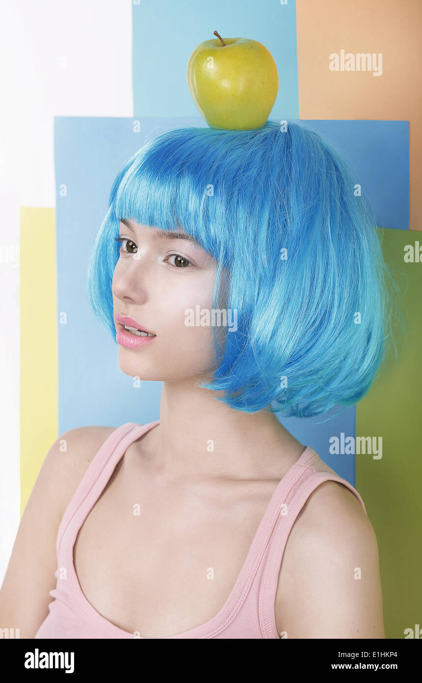 Imagination. Asian Woman in Blue Wig with Apple on her Head Stock Photo