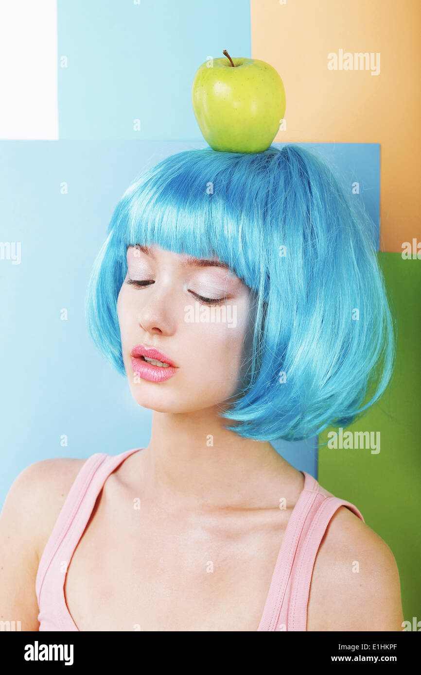 Bizarre Stylized Woman in Blue Wig with Green Apple Stock Photo
