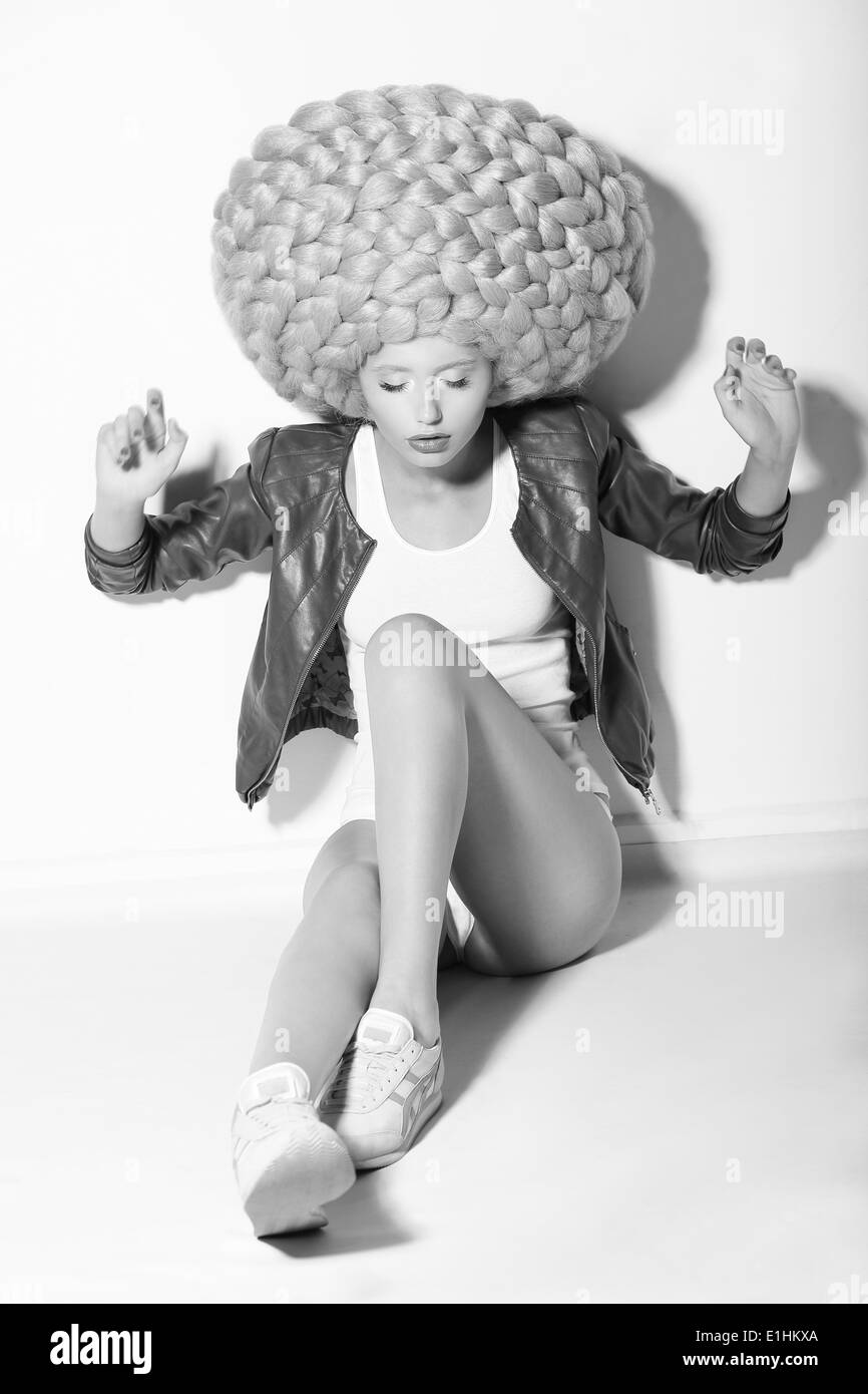 Creativity. Trendy Woman in Huge Fancy Wig sitting on Floor Stock Photo