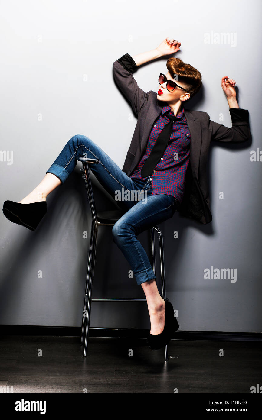 Pinup girl in sunglasses sitting. American retro style. Vintage Stock Photo