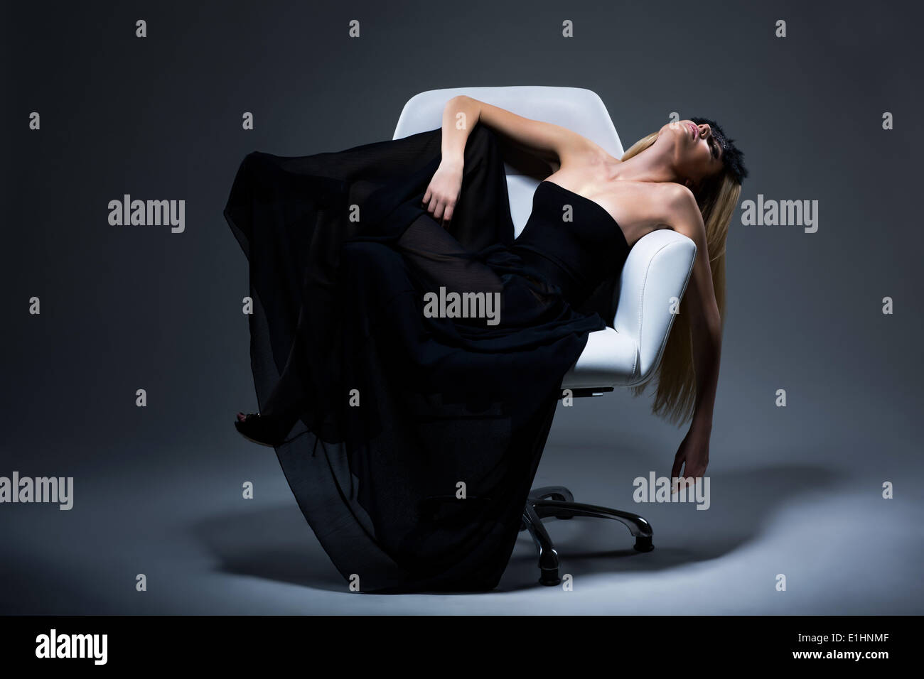 Harmony & Sensuality. Romantic Blond Female in Black Dress resting in Armchair. Satisfaction Stock Photo
