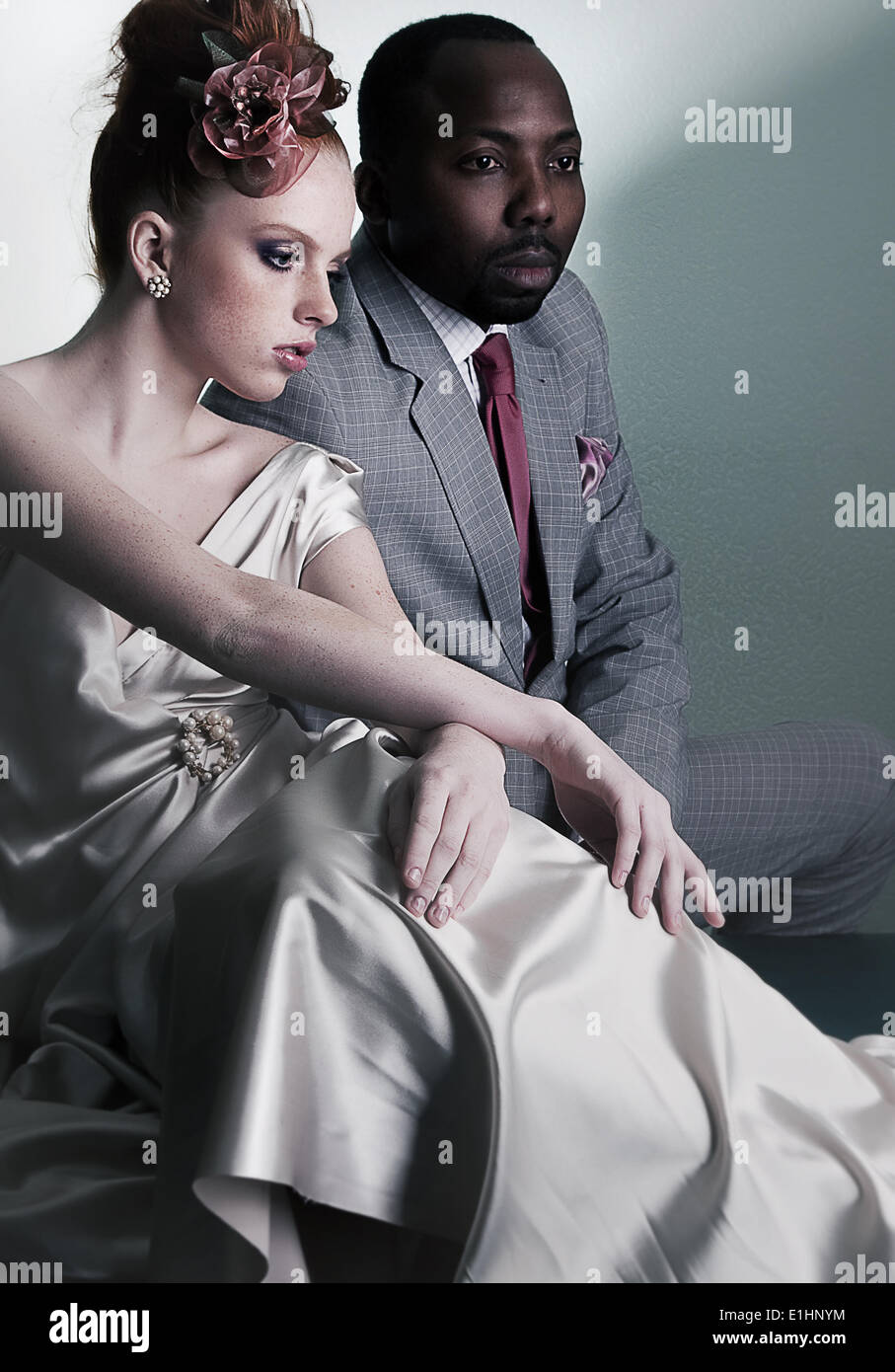 Couple of fashion models sitting - stylish black american man and redhead fashionable woman Stock Photo
