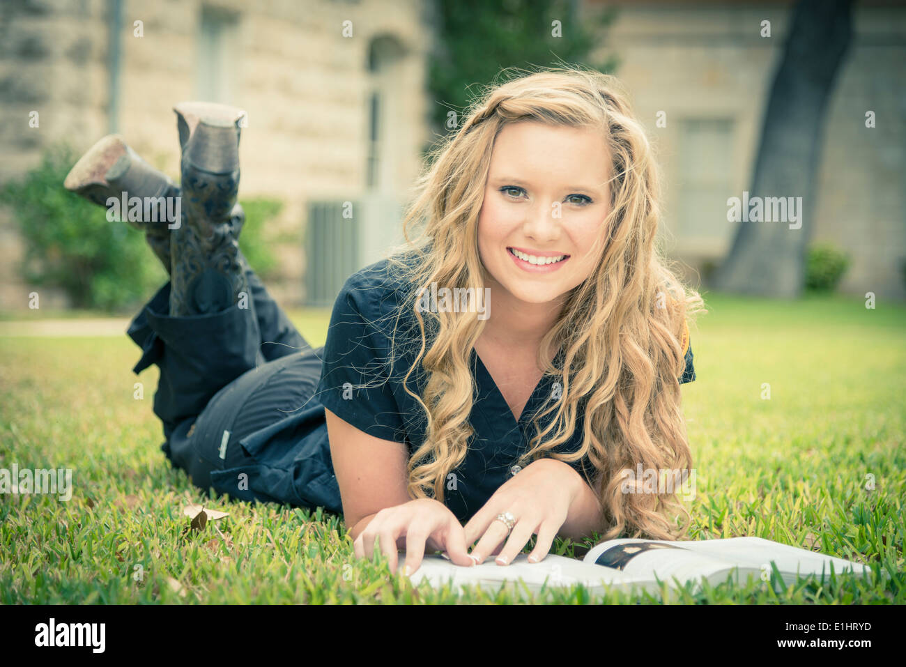 Portrait of smiling young woman lying on grass with a book Stock Photo ...