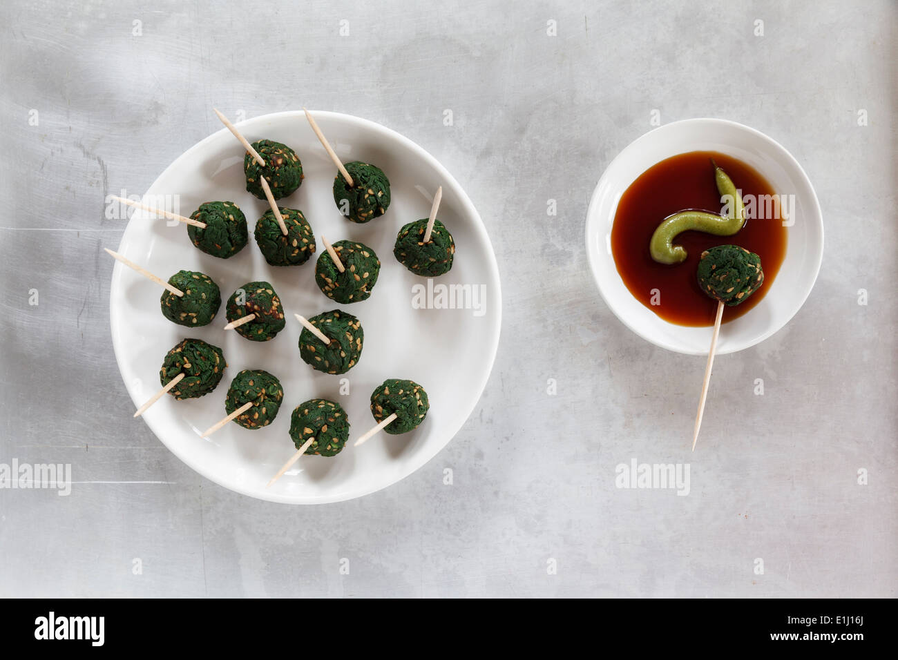 Plate of skewered spinach sesame balls and dipping bowl of sauce