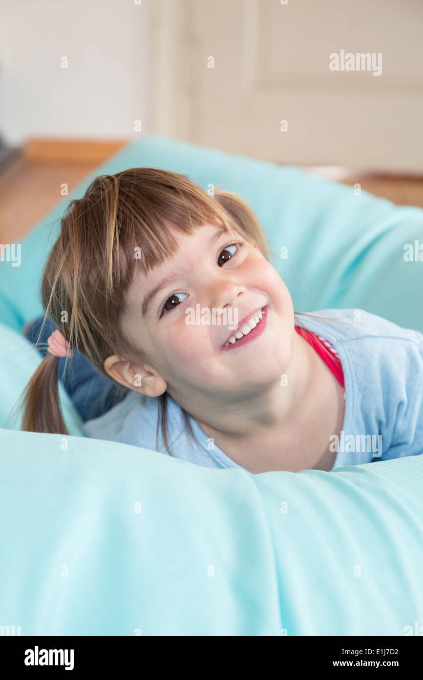 Portrait of smiling little girl lying on bean bag Stock Photo - Alamy