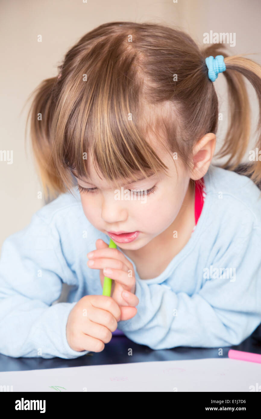 Portrait of little girl with wax crayon looking at her painting Stock ...
