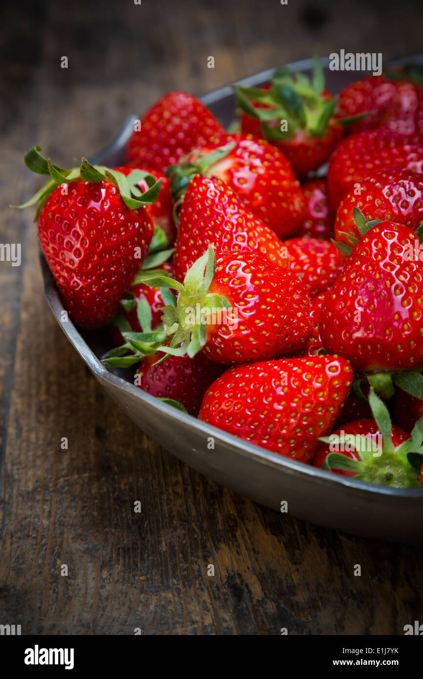 Metal bowl of strawberries on dark wood Stock Photo - Alamy