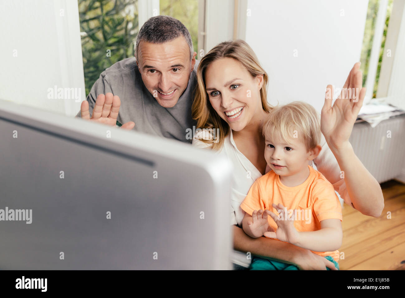 Happy grandfather, mother and son waving at computer screen Stock Photo