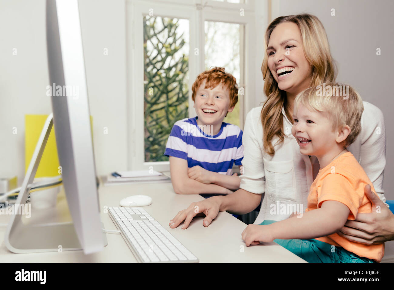 Happy mother with two sons looking at computer screen Stock Photo
