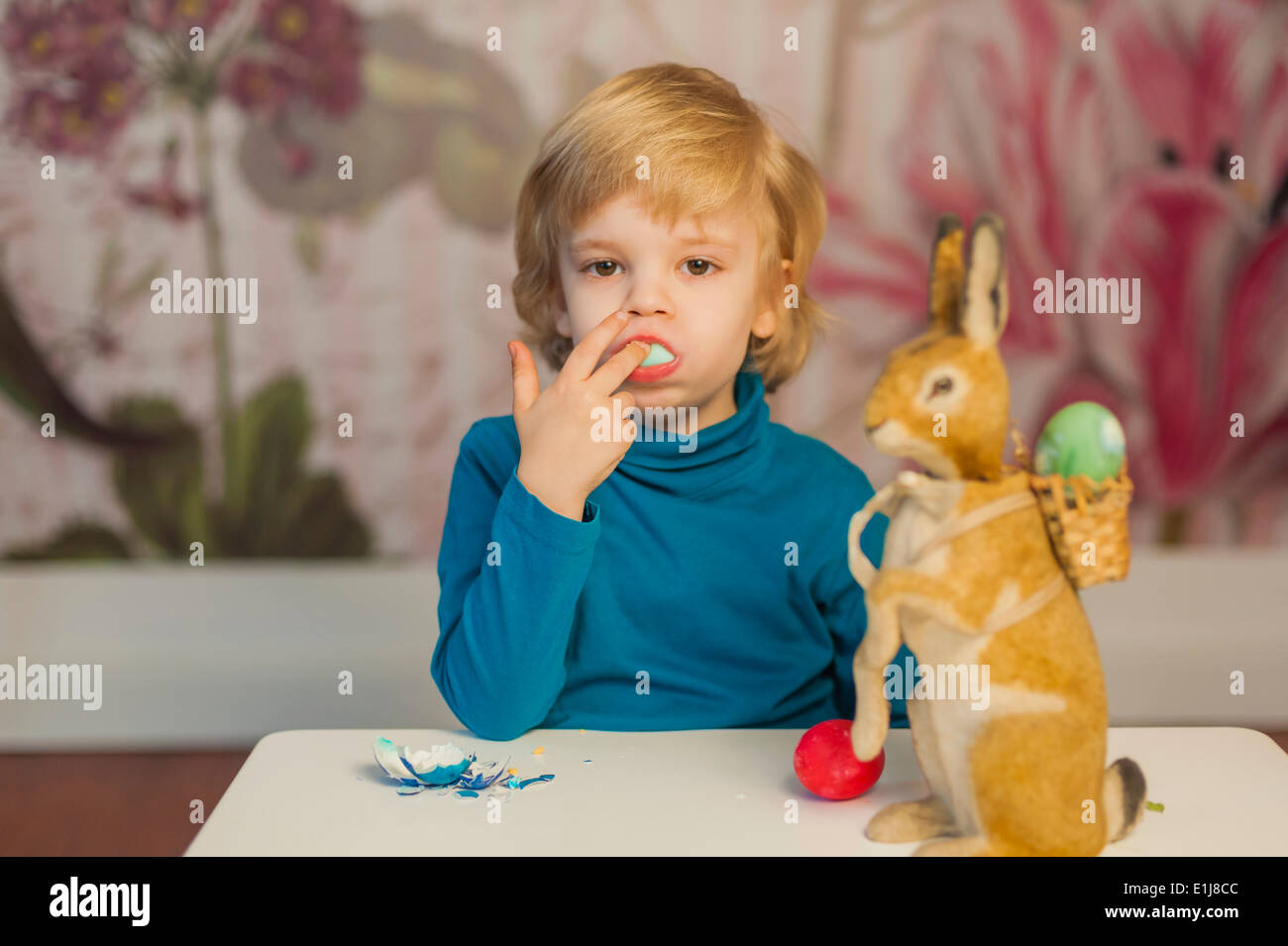 Blond boy with Easter bunny eating egg Stock Photo Alamy