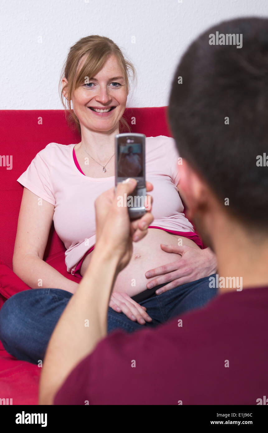 Young man photographing his pregnant girlfriend Stock Photo