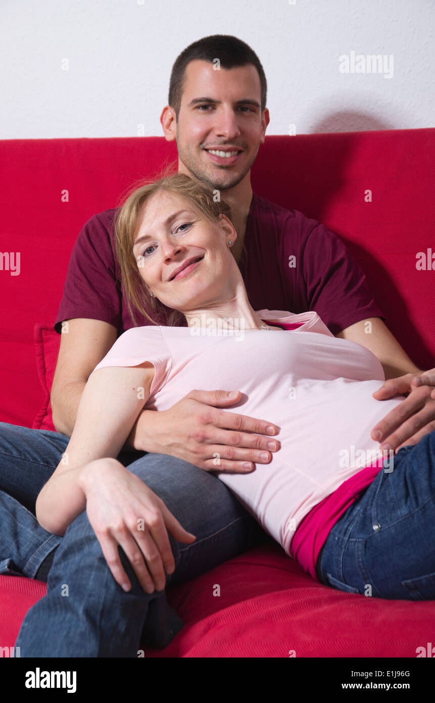 Couple expecting a baby sitting on couch at home Stock Photo
