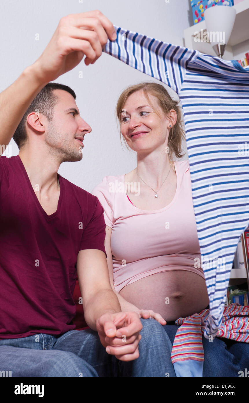 Couple expecting a baby holding rompers Stock Photo