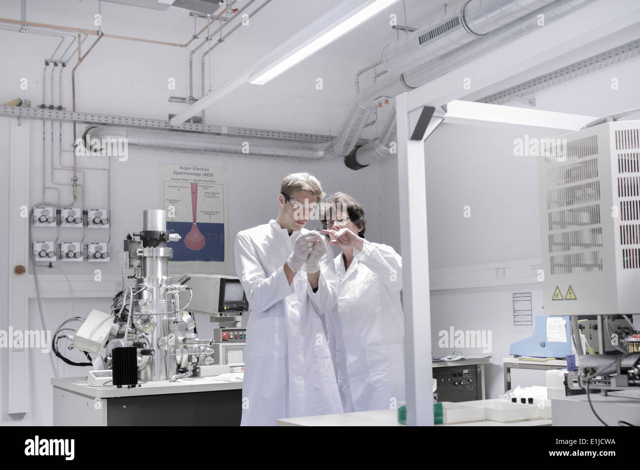 Two scientists standing in analytical laboratory with scanning electron microscope Stock Photo