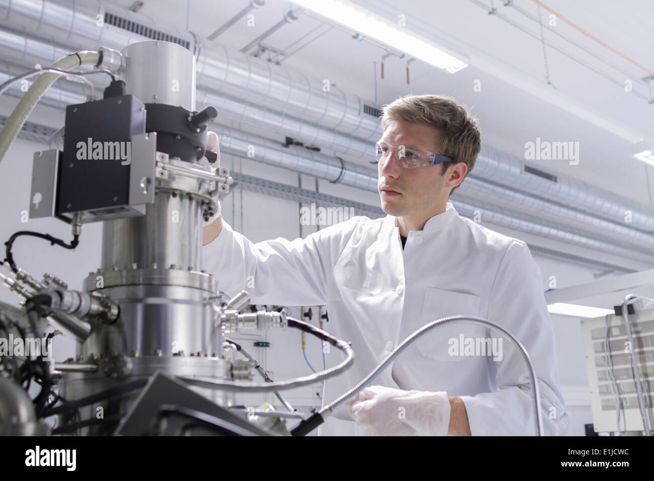 Scientist standing in analytical laboratory with scanning electron microscope and spectrometer Stock Photo