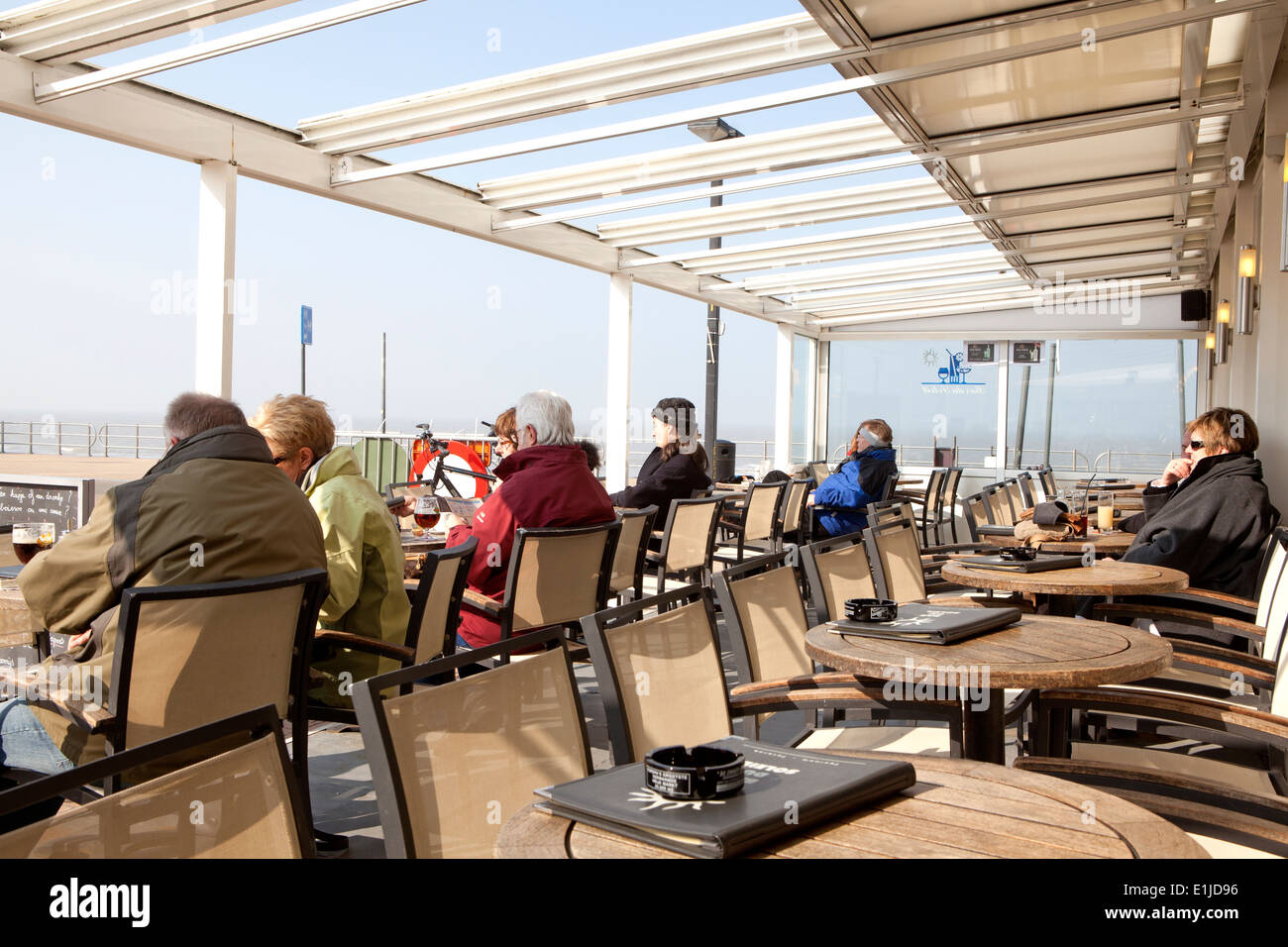 Tourists looking out from promenade cafe toward sea, Ostend, Belgium Stock Photo