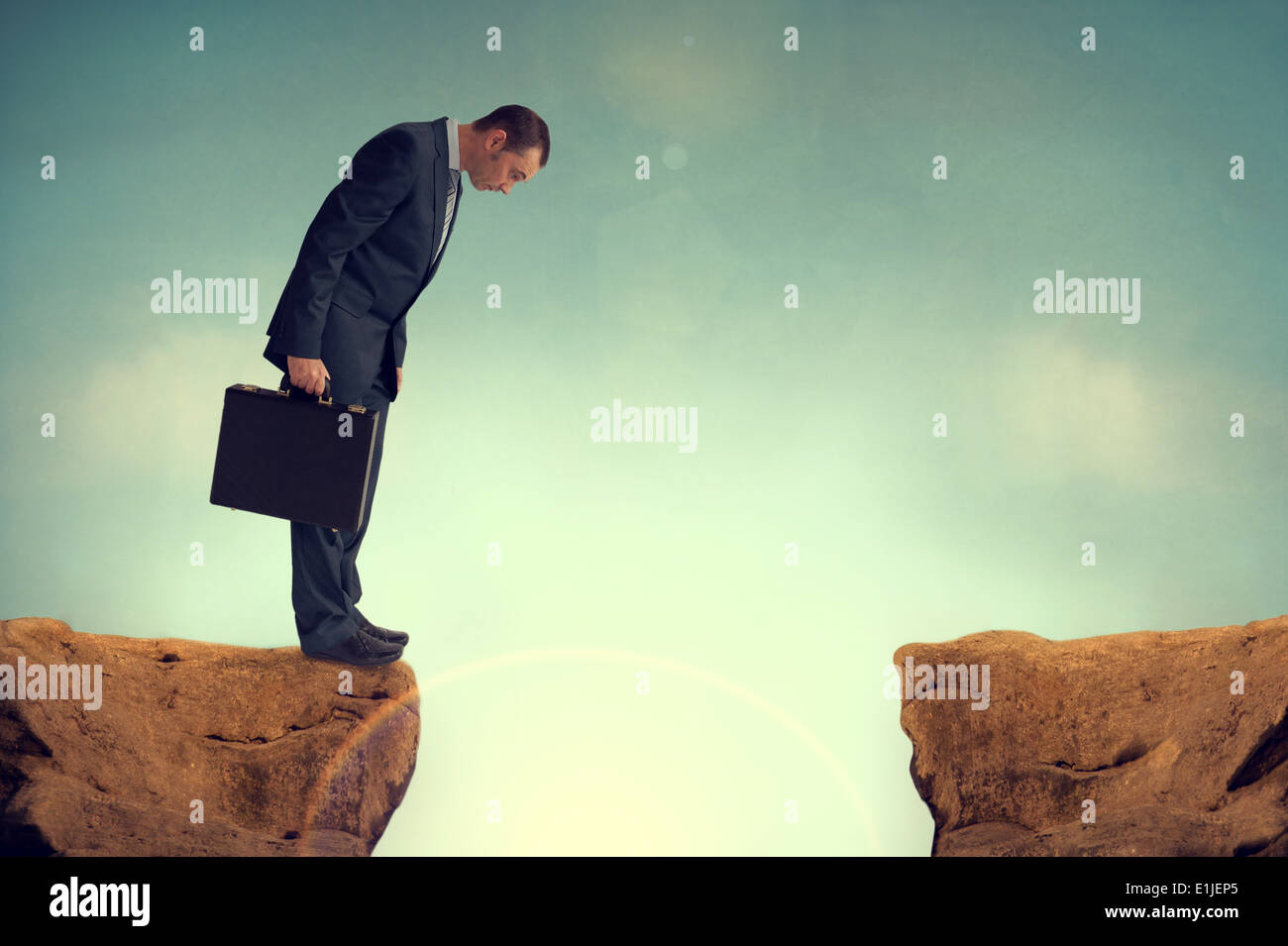 businessman on the edge of a cliff or brink of a crevasse looking down Stock Photo