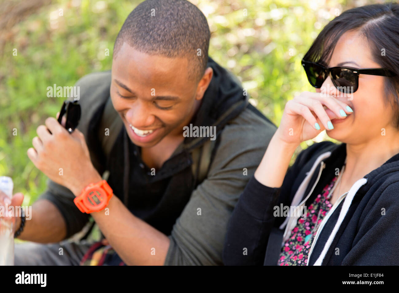 Young couple sitting in park laughing Stock Photo
